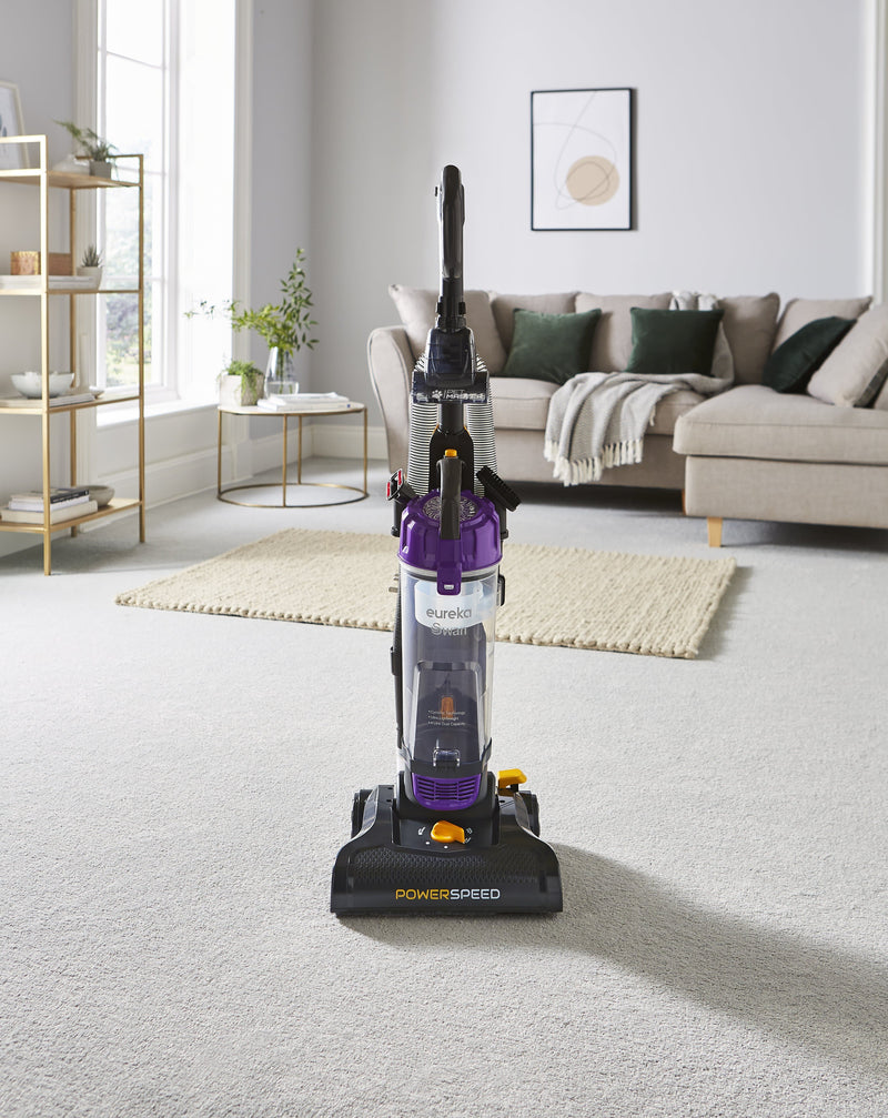 The Swan Powerspeed Upright Pet Extend Vacuum in the middle of a cream living room, with a cream sofa and light brown/cream carpet