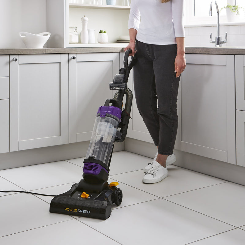 Woman using the Swan Powerspeed Upright Pet Extend Vacuum to clean the kitchen tiles in her white kitchen