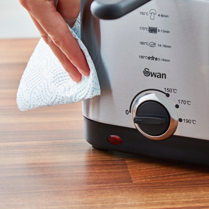 Close-up of a woman's hand cleaning the Swan 1.5 Litre Stainless Steel Fryer with a damp cloth