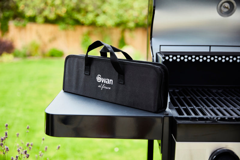 Swan BBQ Tool Set in Swan black bag on top of Swan Kansas 3 Burner Gas BBQ with Side Burner in green garden