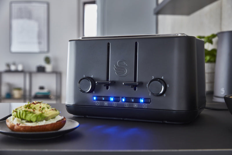 Front view of Swan's Stealth 4 Slice Toaster in a sleek, modern kitchen, next to a sliced bagel with cream cheese and smashed avocado